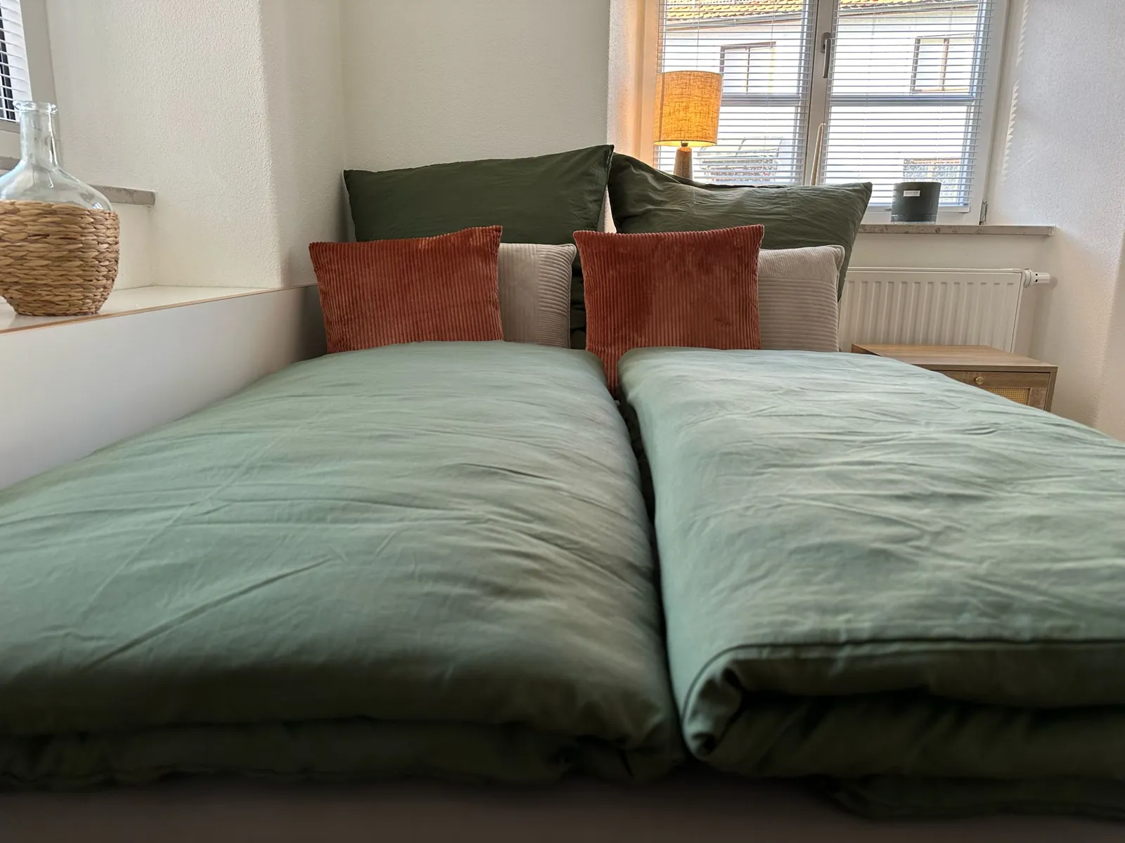 Ferienwohnung Lieblingsort – Doppelbett mit grüner Bettwäsche und Cord-Kissen