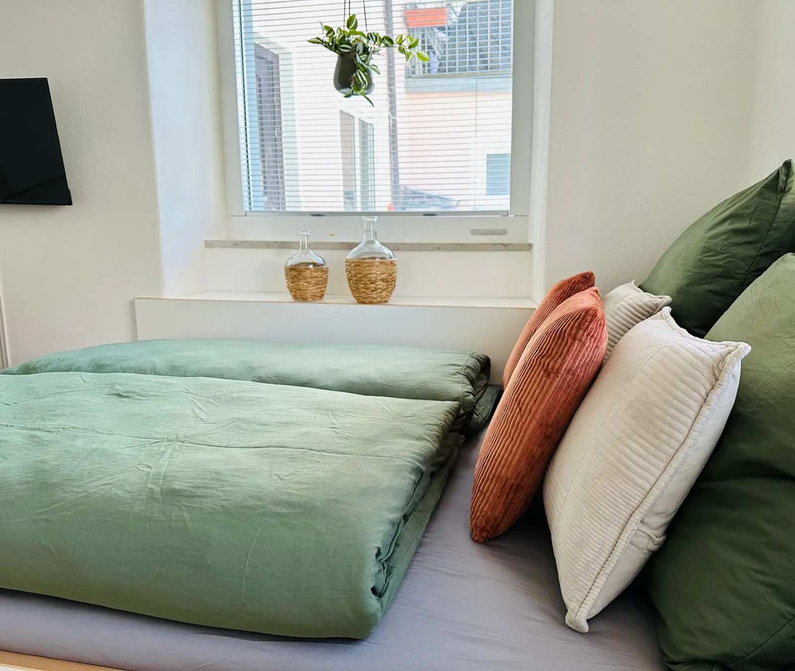 Ferienwohnung Lieblingsort – Bett mit Kissen und Blick zum Fenster